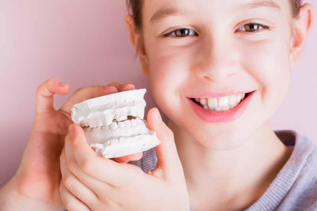 Young girl holds a plaster cast of her teeth