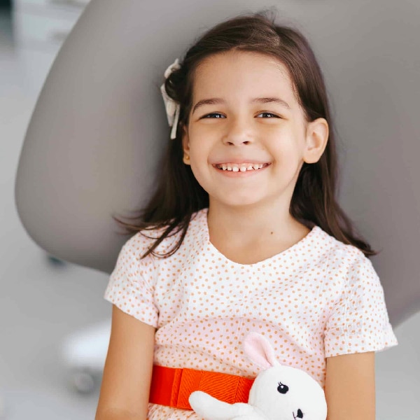 Young girl sitting in dentist chair smiling